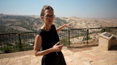 Lucy Williamson pointing to E1 settlement, seen on the right