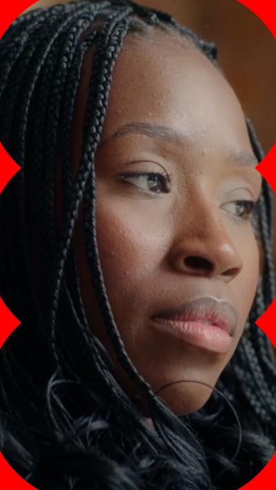 A woman with long dark hair in braids looks off-camera