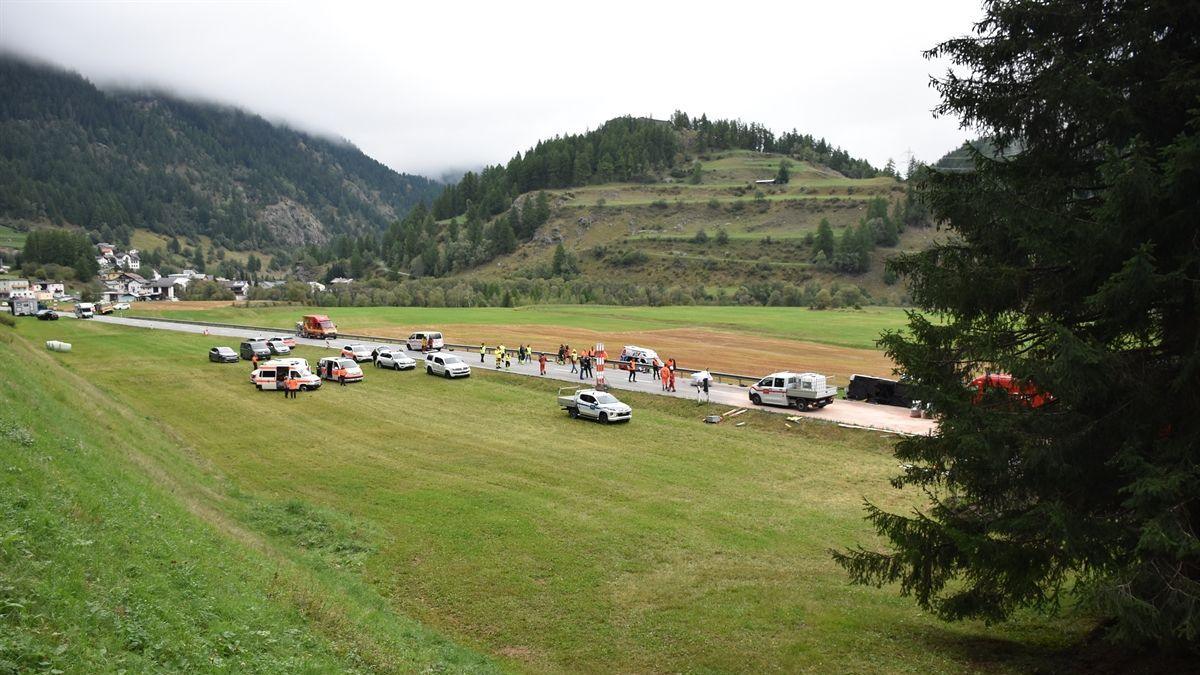 Several emergency services cars seen on the grass near the upturned coach, as fog is seen settled on hills in the background