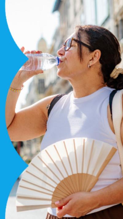A woman drinks from a bottle of water while holding a fan