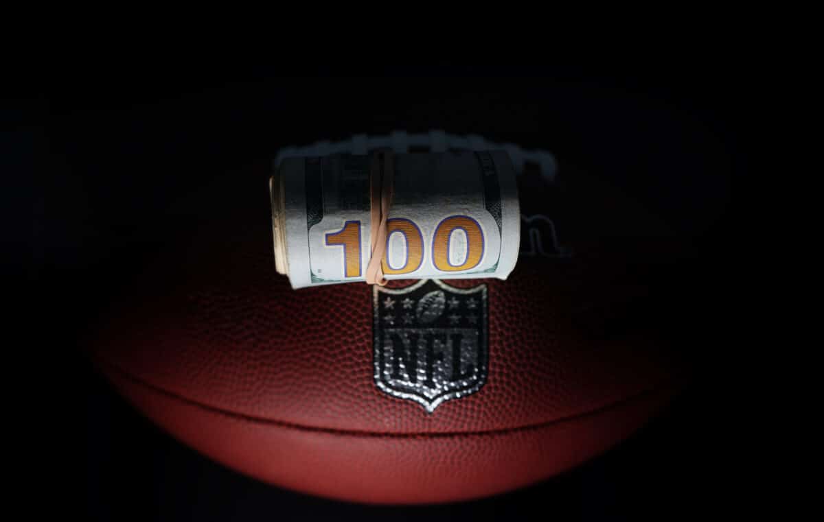 An NFL football with a wad of cash on top of it