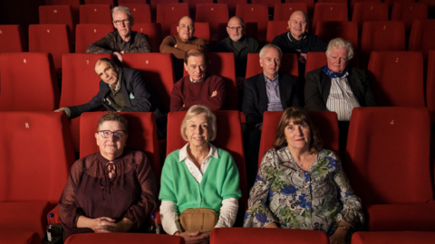 The cast of 70 Up pose for a photo in a cinema.