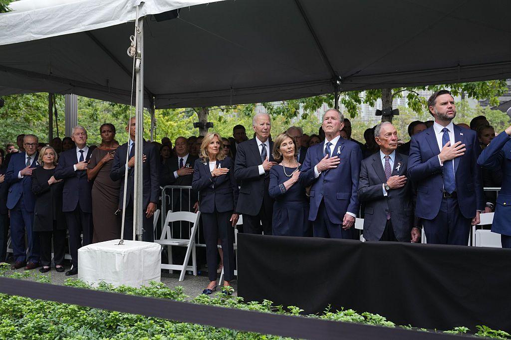 Former US presidents and first ladies stand under a tent with their hands on their chest. Also in frame is current vice president JD Vance and former New York Mayor Michael Bloomberg.