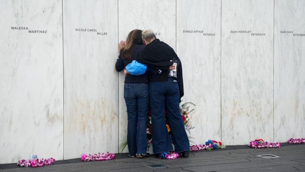 Paula Jacobs, sister of Flight 93 victim Louis J. Nacke II and cousin Mary White Henderson, lean on the Wall of Names, at the Flight 93 National Memorial.