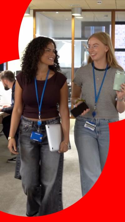 Two young women walking in an office