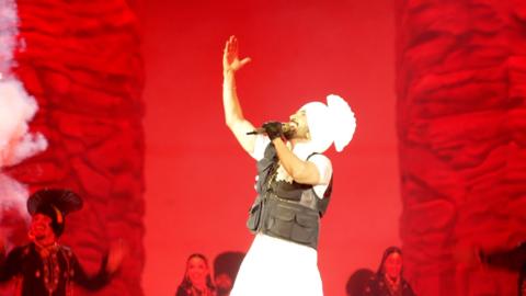 Diljit Dosanjh performing at Wembley Stadium against a red backdrop
