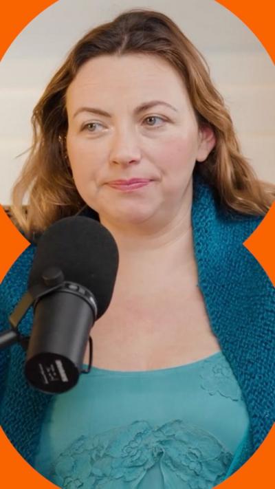 Charlotte Church is sitting behind a microphone. She has way brown hair. She is wearing a turquoise top with a teal wrap over her shoulders.