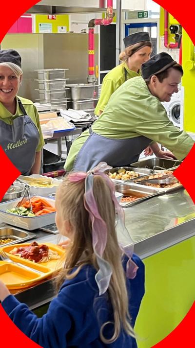 Food, including hash browns and pizza, being served to students waiting with their trays