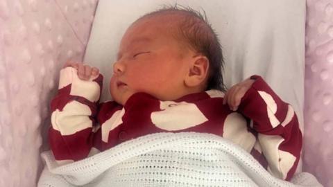 A baby in a red baby grow