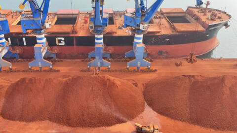 Cette photo, prise le 26 mars 2026, montre des grues en train de décharger de la bauxite importée de Guinée dans un port de Yantai, dans la province du Shandong, à l'est de la Chine.