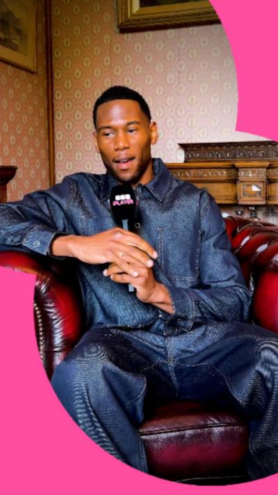 YouTuber and boxer King Kenny wearing a suit speaking into a microphone.