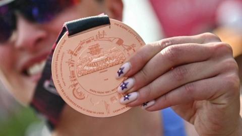 Close-up of London Marathon medal being held by a smiling woman