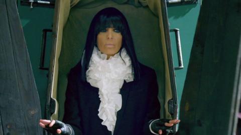 Claudia Winkleman emerging from a coffin