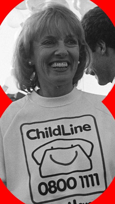 A black and white photo of Rantzen smiling wearing a Childline sweater, surrounded by balloons