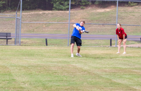 A batter about to hit a wiffleball with a catcher behind them