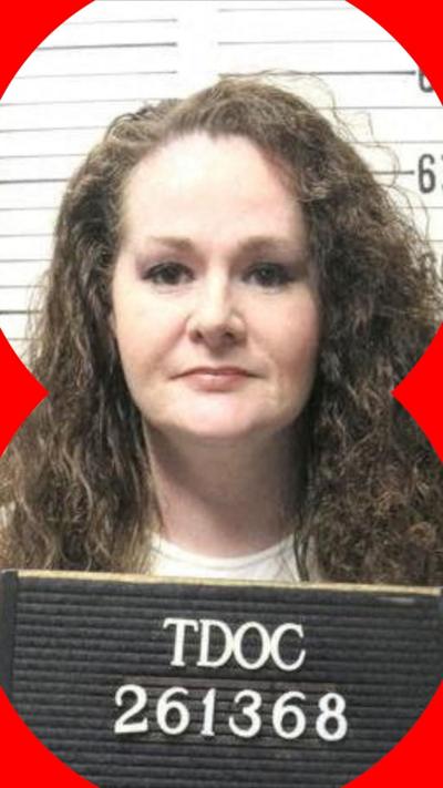 Christa Pike has long auburn hair. She is standing in front of a height chart and holding up a sign with an identifying number.
