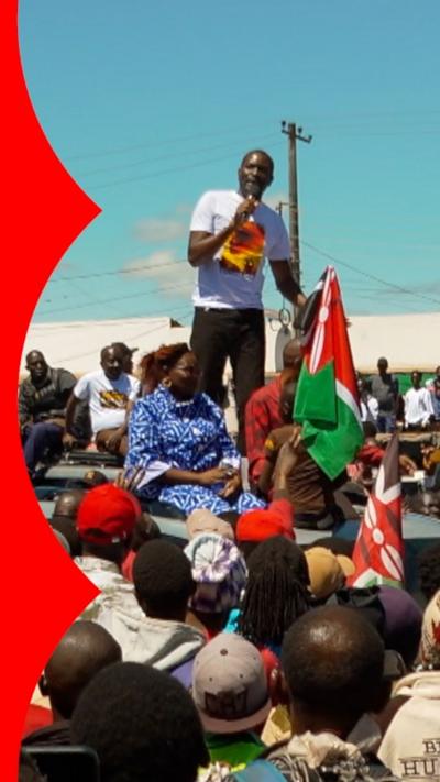 A man speaking into a microphone and holding a flag