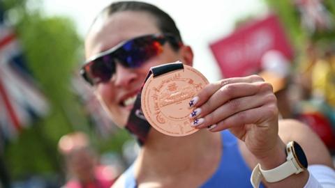 Close-up of London Marathon medal being held by a smiling woman