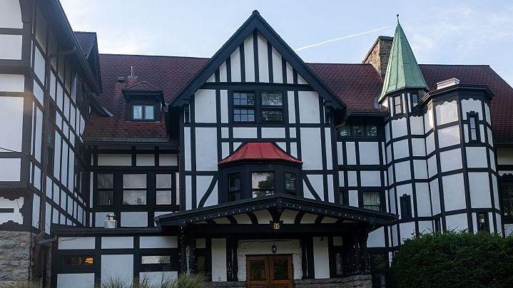 A large, black and white white multi-storey house with a red tiled roof. 