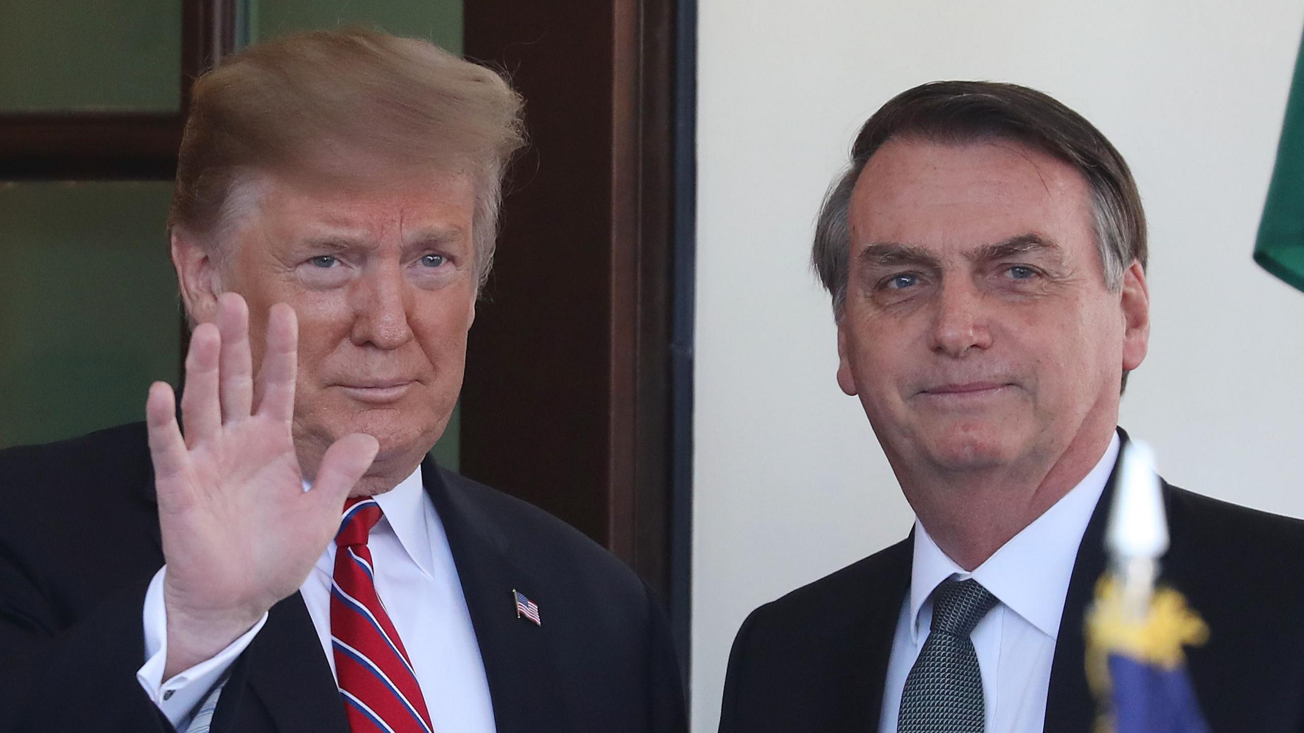 Trump, with a waving hand, stands next to Bolsonaro outside the White House. 