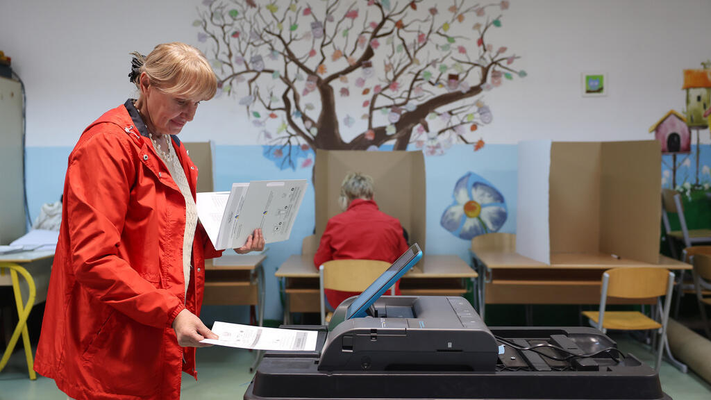 A woman places her ballot into an electronic ballot box during the general election in Sarajevo, Bosnia, Sunday, Oct. 4, 2026.