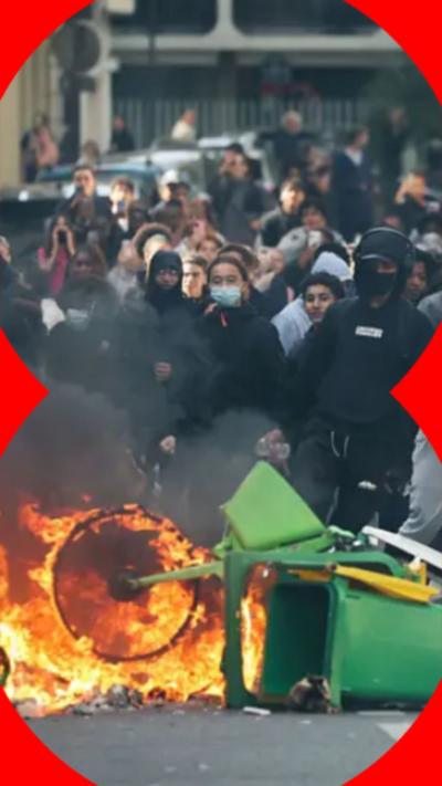 A group of protestors on the street burning a bike and bin.