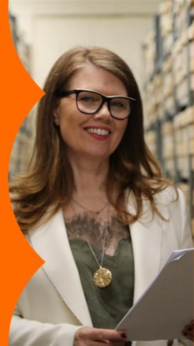 Nuala McGovern has long red hair, is wearing glasses and is holding a paper script.