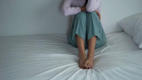 Stock photo of a woman sitting on a bed 