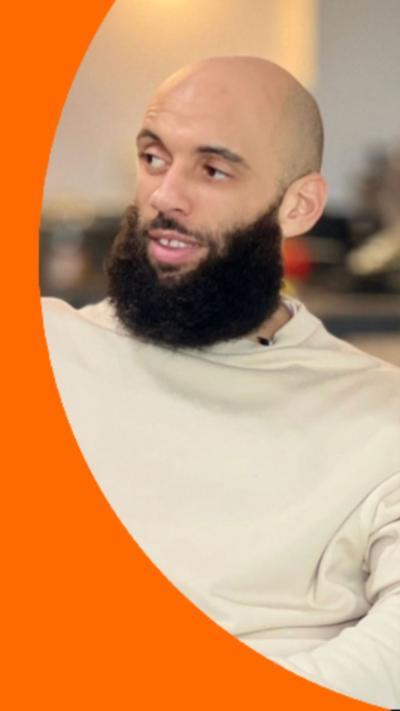 A bald man, Aaron Dale, with a dark beard wearing a cream jumper.