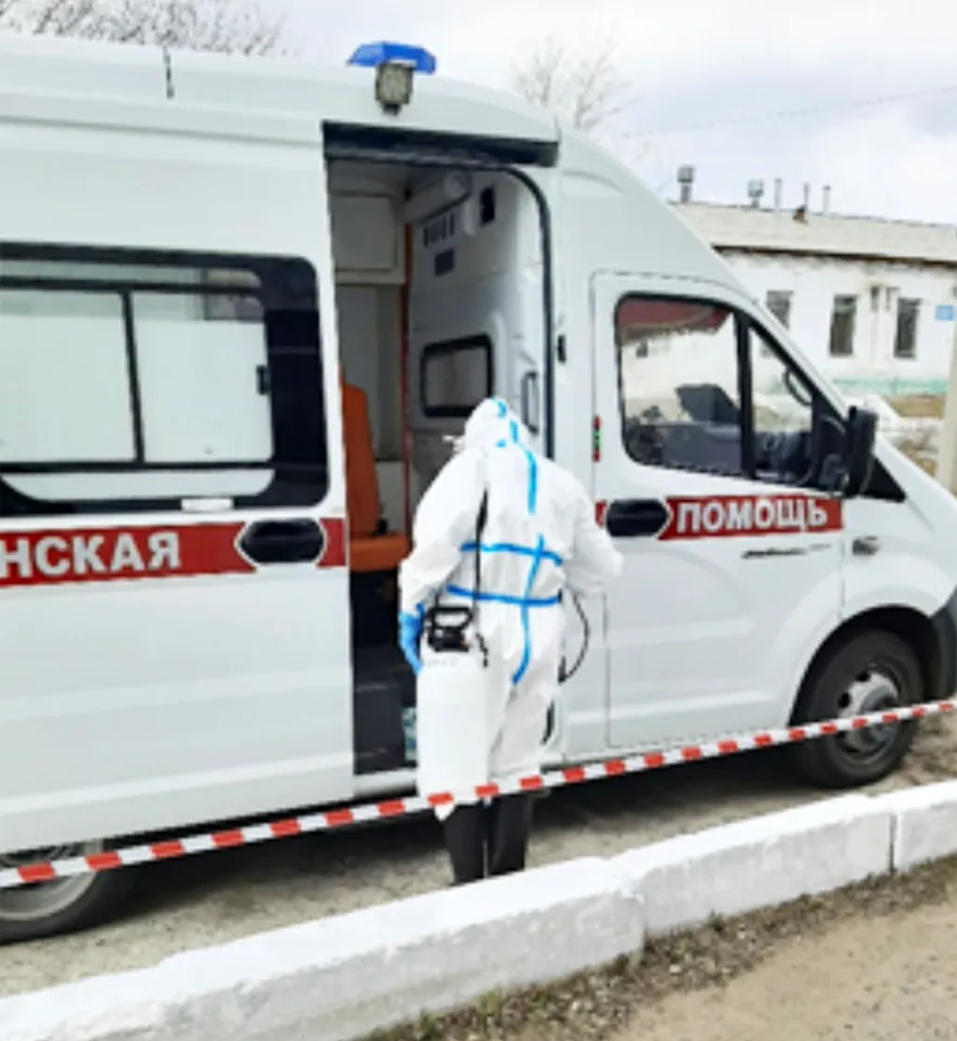 A person in protective gear disinfects an ambulance.