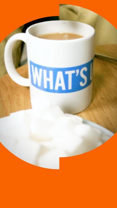 Somebody picking up a sugar cube with some tongs and adding it to mug of tea.