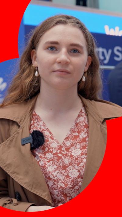 A young woman with a coat and a blouse looking into the camera at the Conservative party conference 