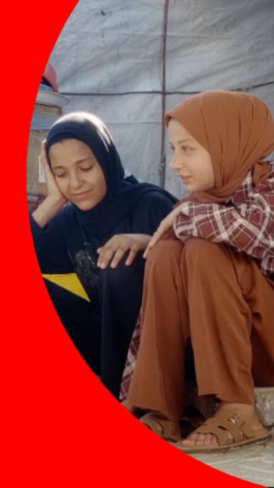 Two young girls sat on a step. One (left) is dressed in all black, the other (right) is dressed in light brown.