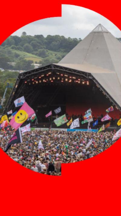 Glastonbury Pyramid stage with a large crowd and flags.
