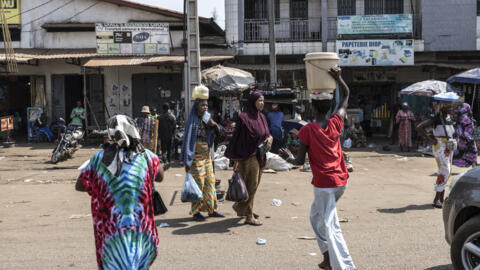 Des piétons traversant une rue dans le quartier de Cosa à Conakry, le 26 décembre 2025.