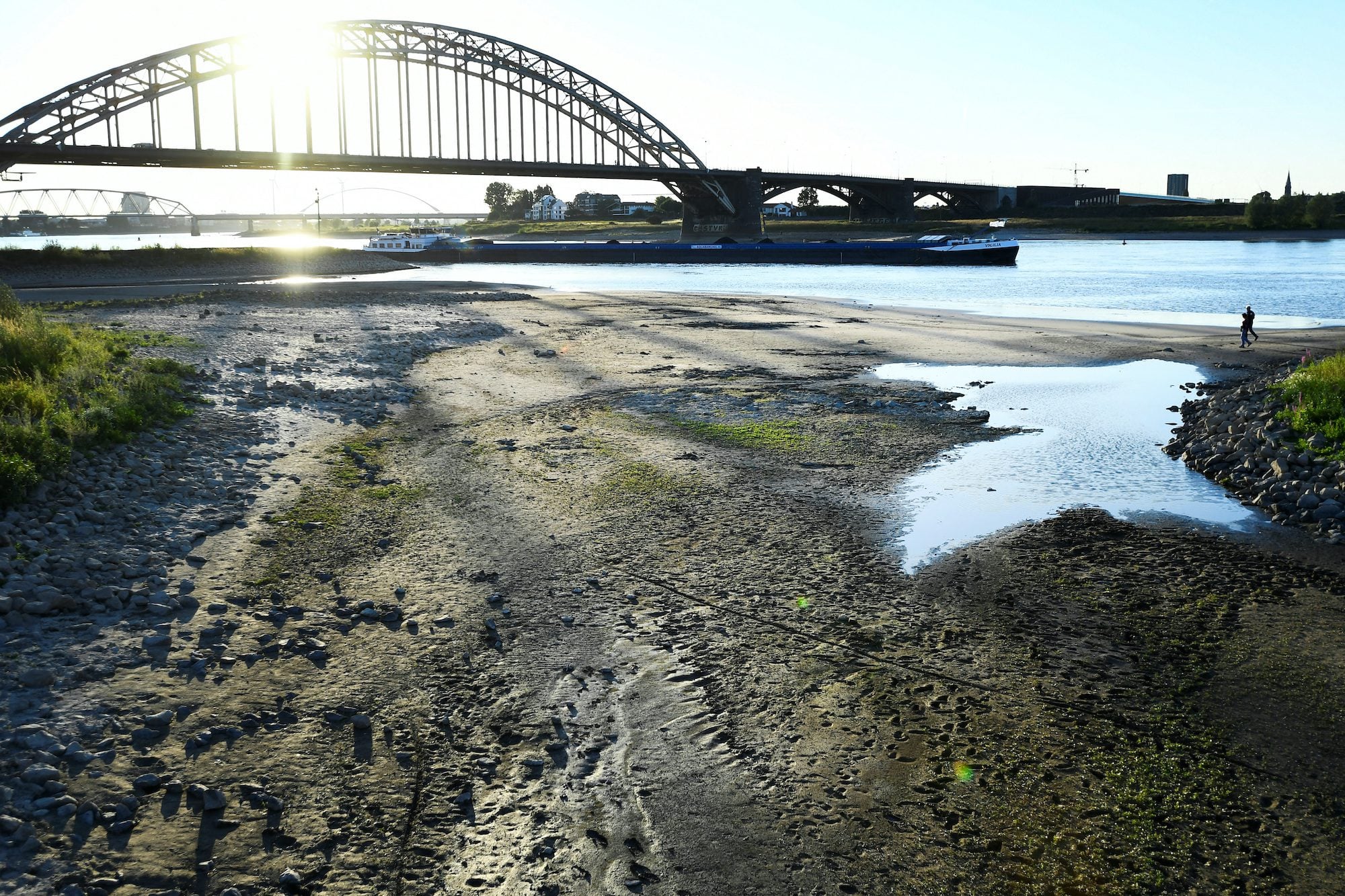 An inland vessel passes a river bed that is almost dry due to low water levels of the Waal River in Nijmegen, Netherlands August 7, 2022. REUTERS/Piroschka van de Wouw