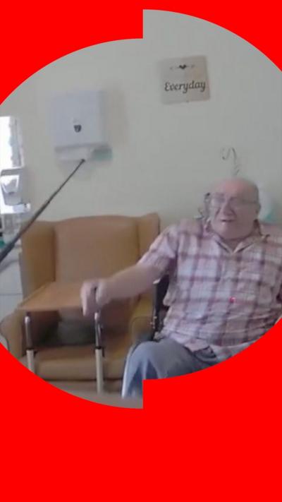 Body-worn camera footage of a man sitting in a chair. Someone out of shot is raising a baton towards him.