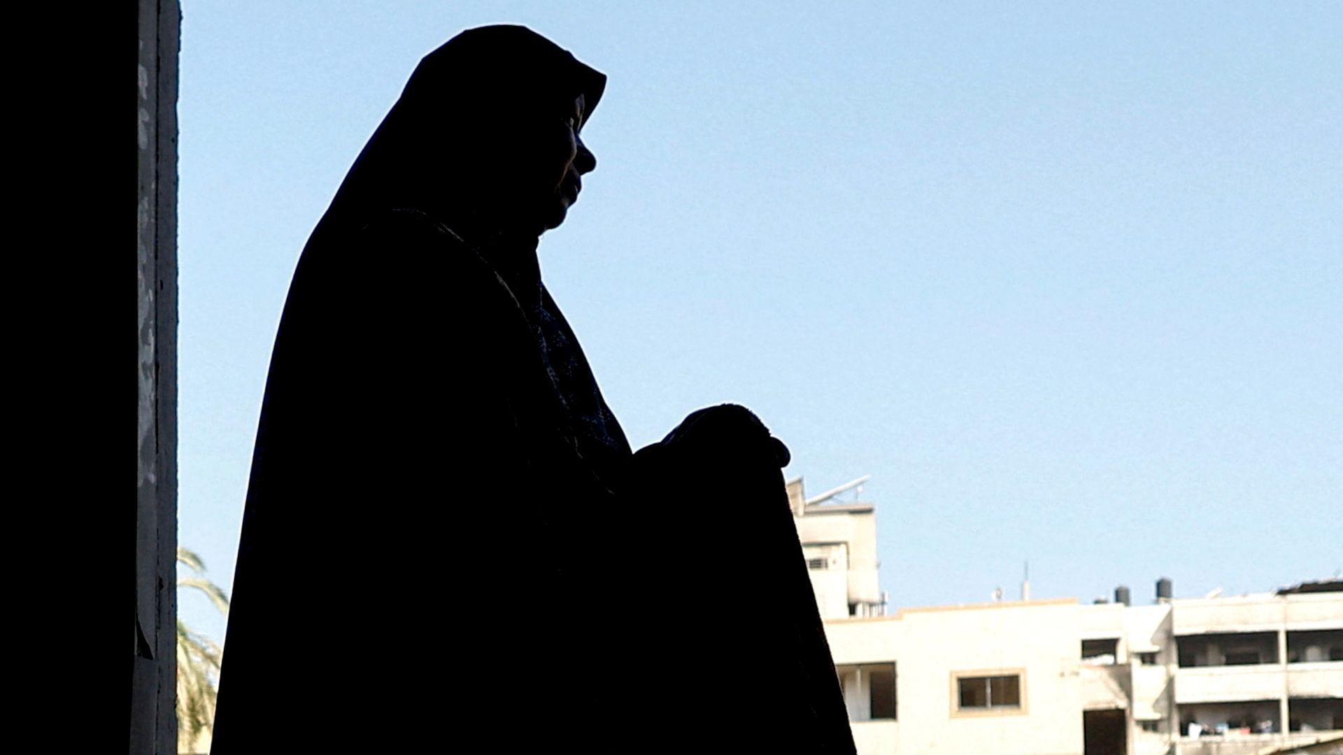 A file photo showing a Palestinian woman inspecting her damaged home after an Israeli strike on a nearby mosque, in Gaza City (29 July 2026)