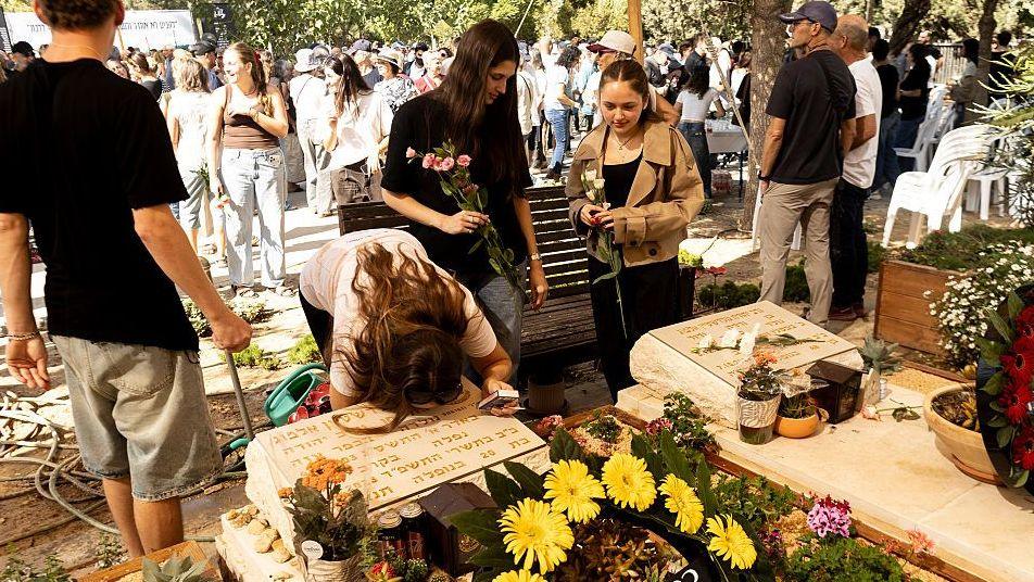 Kibbutz residents and relatives pay tribute beside graves 