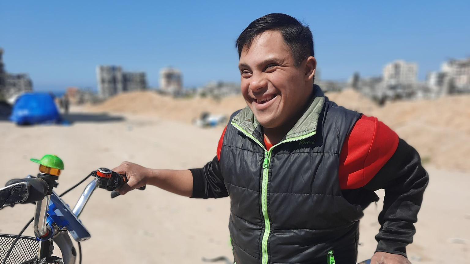 Ahmed al Madhoun smiles as he holds his bike. 