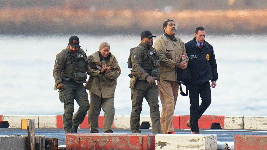 Nicolas Maduro and his wife, Cilia Flores, are seen in handcuffs after landing at a Manhattan helipad, escorted by heavily armed Federal agents as they make their way into an armored car en route to a Federal courthouse in Manhattan on January 5, 2026 in New York City. 