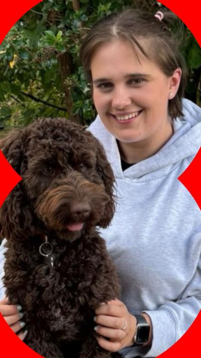 A woman with short brown hair sits with a dog in on her knee
