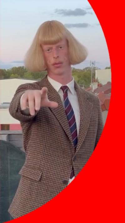 Man with blonde bob pointing at camera
