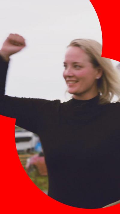 Susanne standing outside with her fist raised in the air in a salute of celebration 