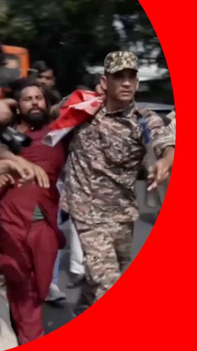 Man in red outfit being held by man in police uniform
