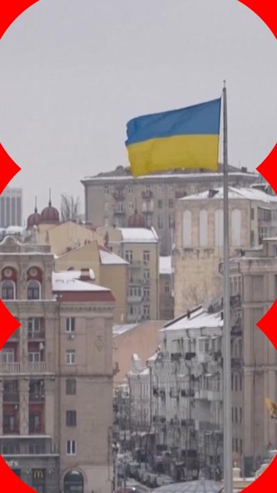 A Ukrainian flag is flying in a city with snow on rooftops.