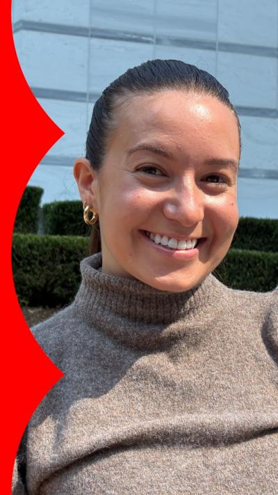 A woman with dark hair pulled away from her face smiles at the camera