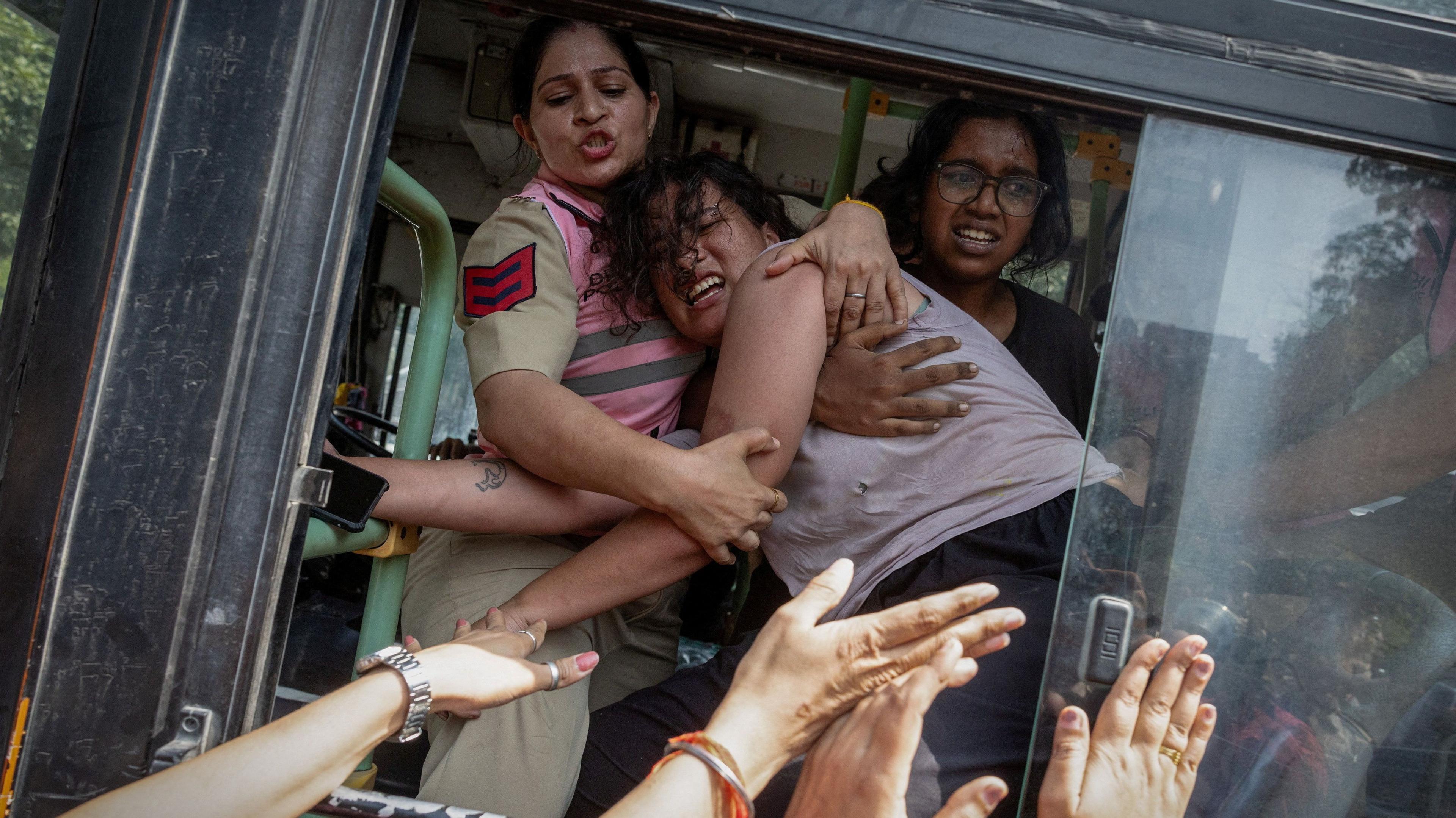 Policewomen try to stop a detained protestor to escape from a bus during a protest by the Cockroach Janta Party (CJP) seeking the resignation of India's Chief Election Commissioner Gyanesh Kumar, near the protest site in New Delhi, India, October 10, 2026. REUTERS/Adnan Abidi TPX IMAGES OF THE DAY