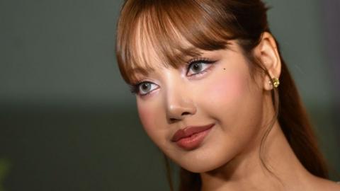 Lisa Manobal is pictured on a red carpet, looking off camera. A camera flash illuminates her eyes