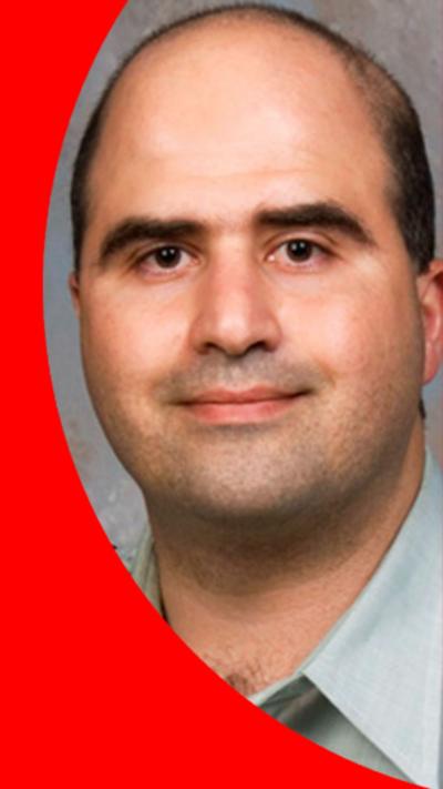 A man with short hair smiles at the camera
